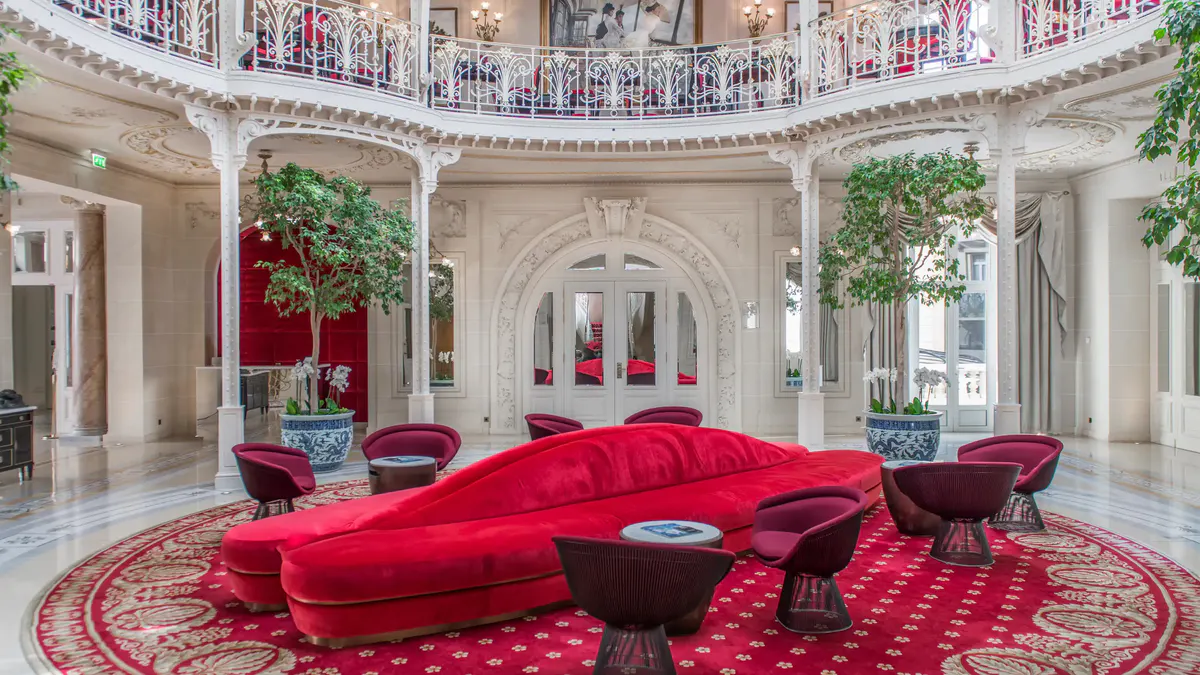 Grand interior with red-upholstered curved seating, mirrored walls and painted dome ceiling
