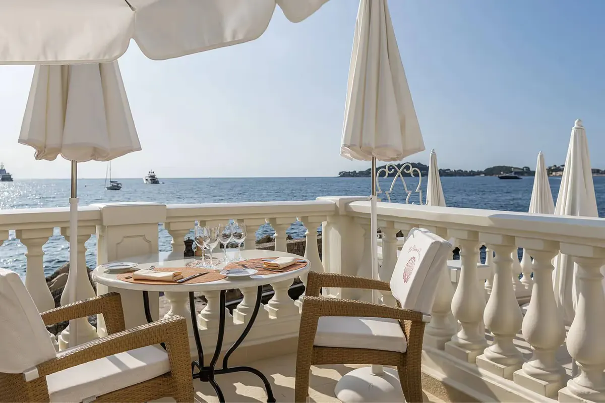 Outdoor terrace dining with white umbrellas and sea views