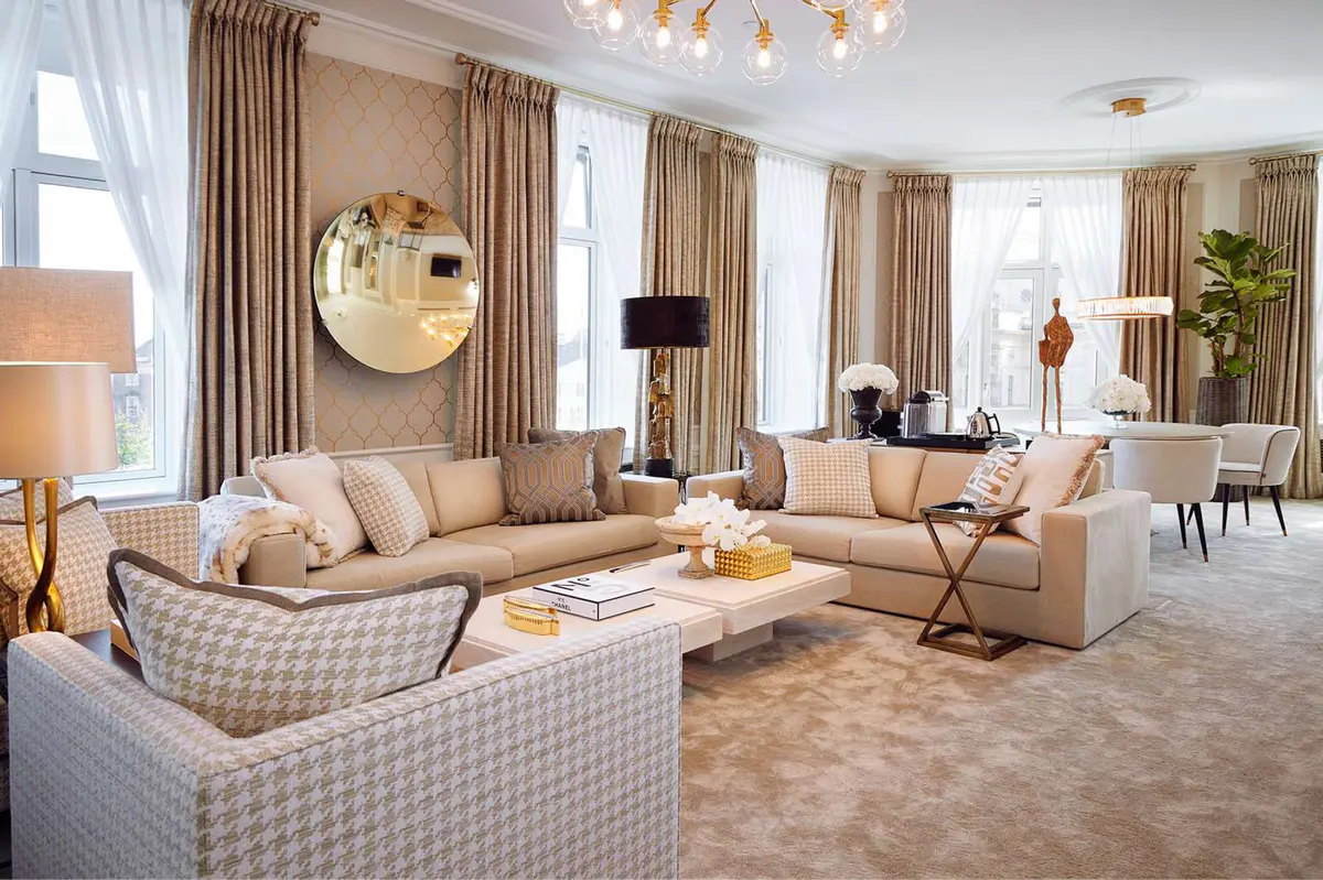 Spacious suite with patterned sofas, round mirror, and tall windows