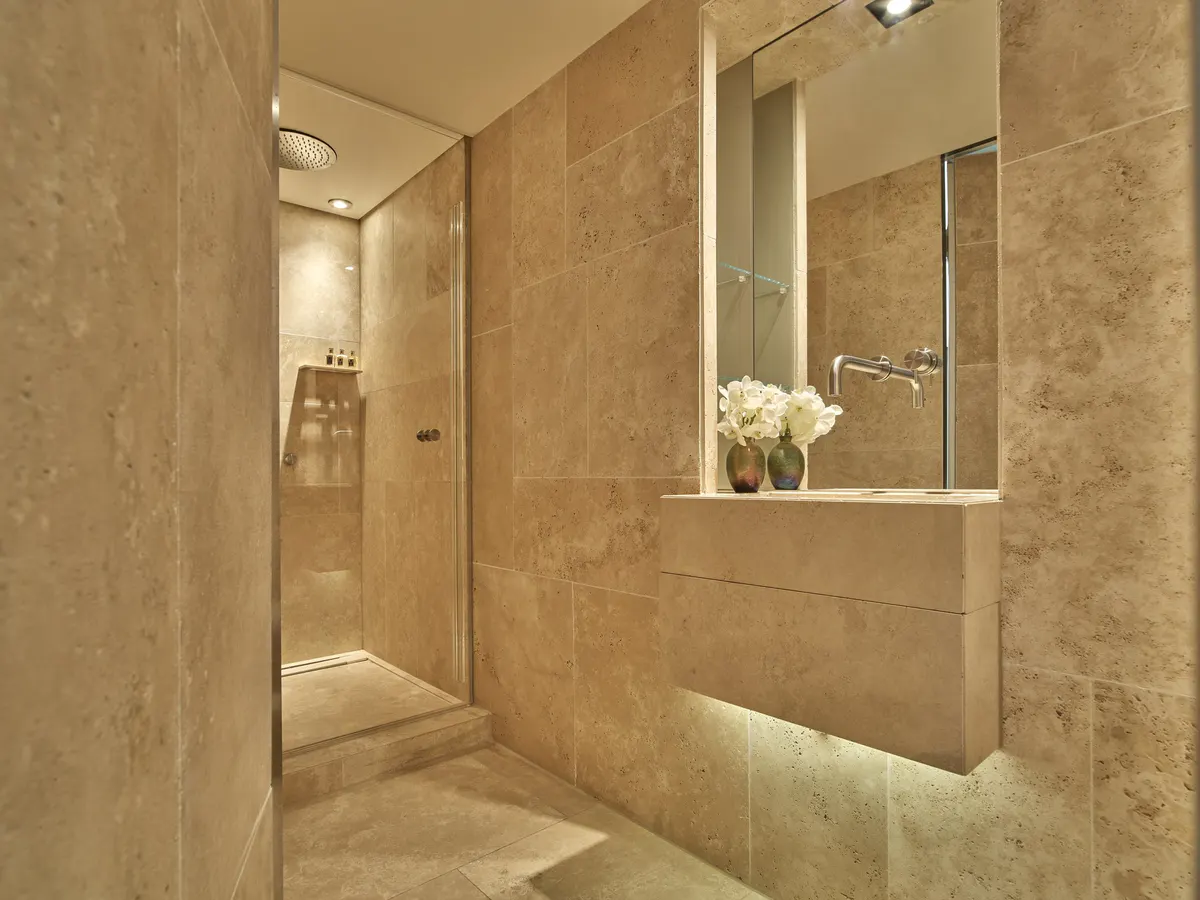Modern marble spa bathroom with walk-in shower, built-in wall niche, and soft lighting