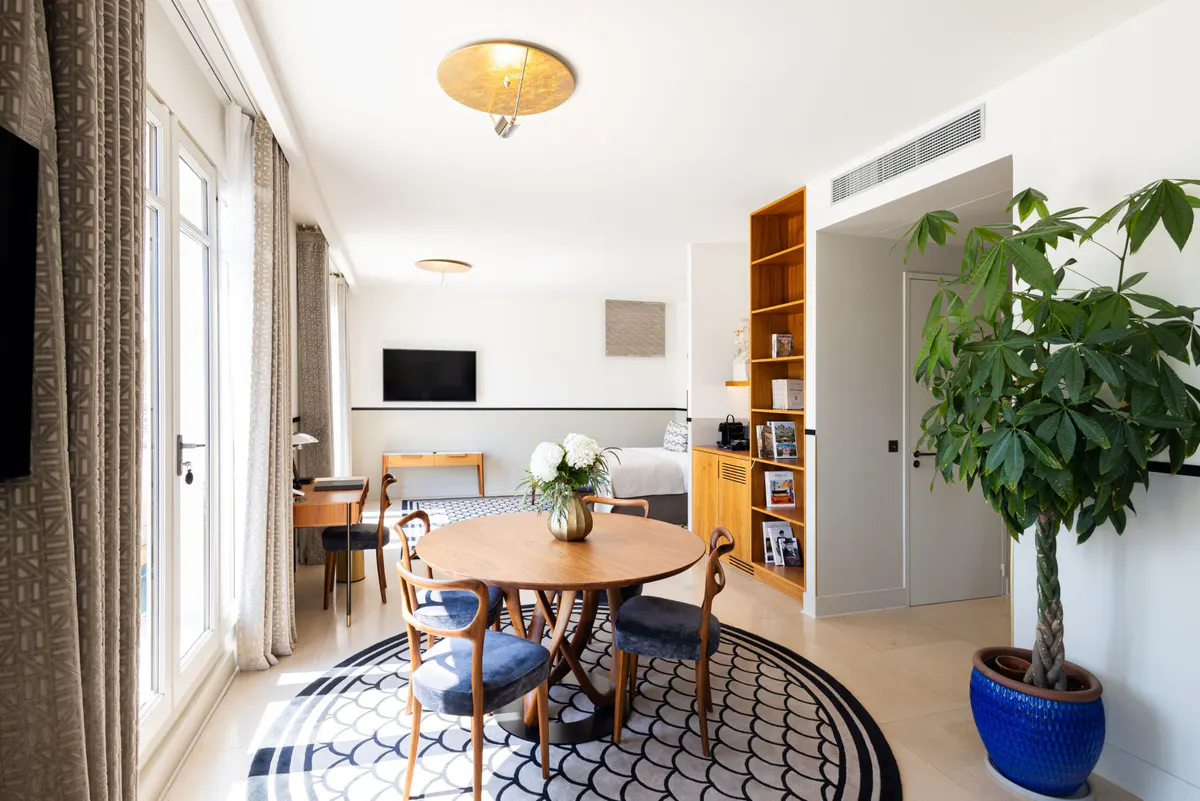 A suite with wooden furnishings, geometric rug, and living area with dining space visible