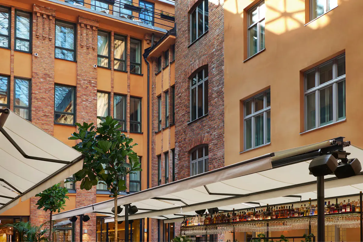 Colorful brick courtyard building with outdoor cafe seating and shade structures