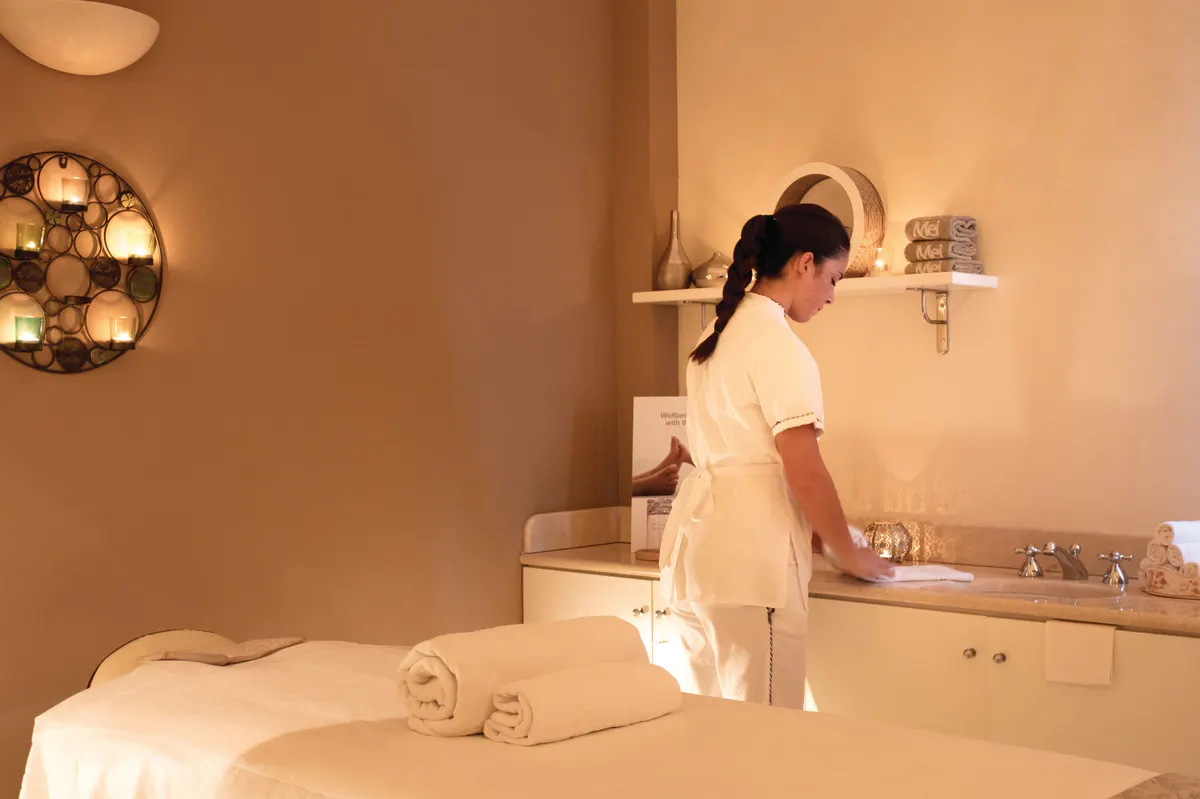 A spa therapist preparing for a treatment in a light-filled wellness space