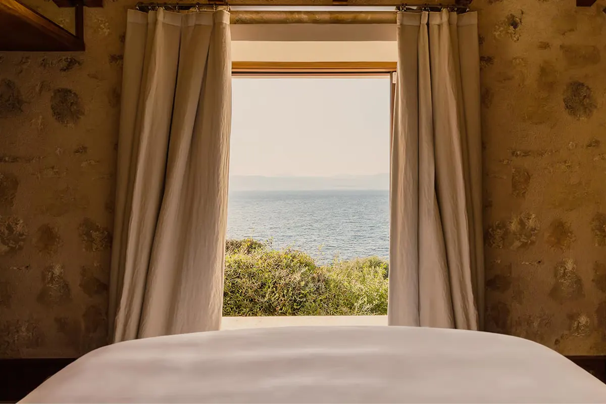 A covered terrace with cushioned loungers, wooden beams, and views of the Bay of Palma