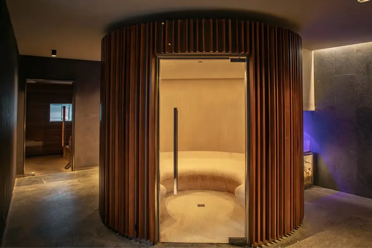 Spa steam room with curved wood interior and ambient lighting