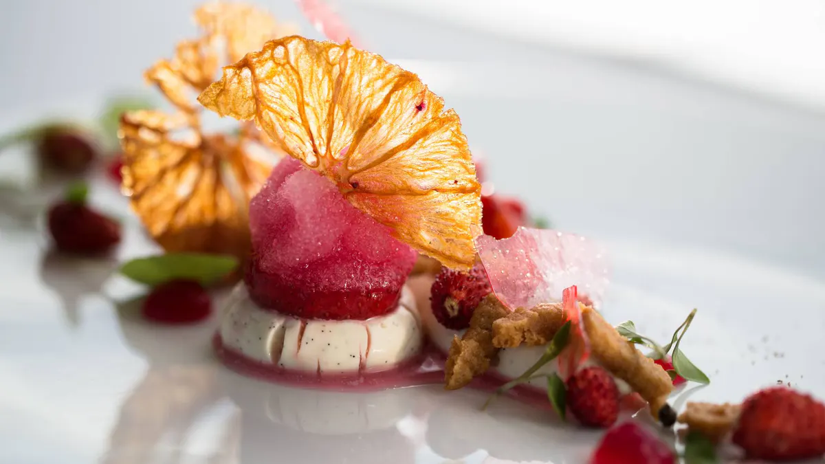 Plated dessert with crystallized citrus and berry garnish