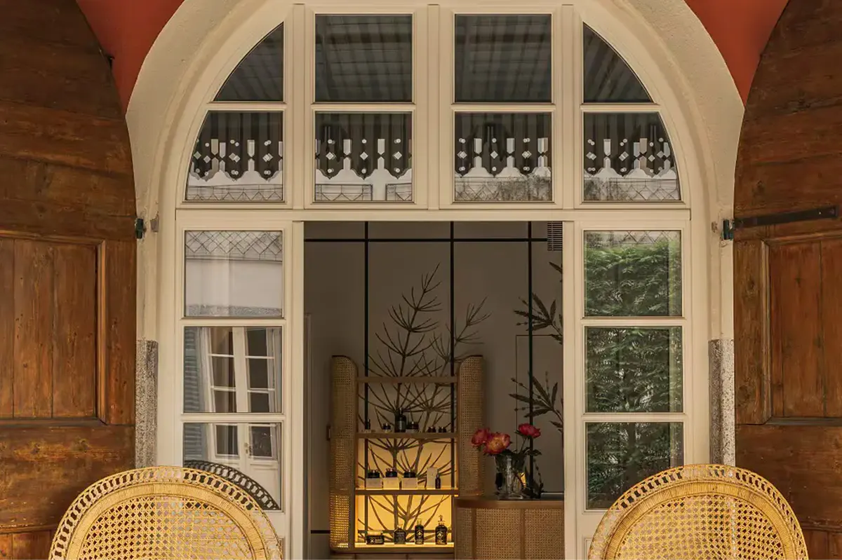 An arched glass door opening to green grounds and distant lake landscape
