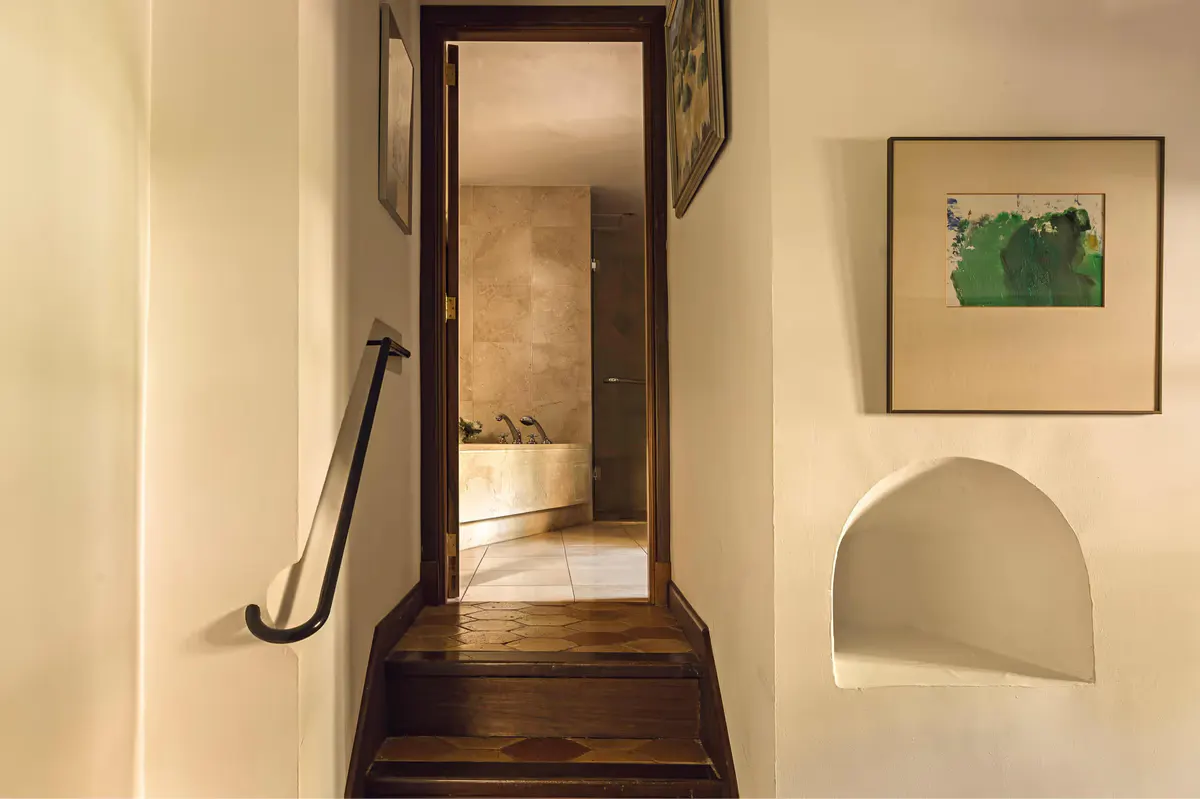 Staircase with dark wooden steps leading upward past a framed painting and archway doorway