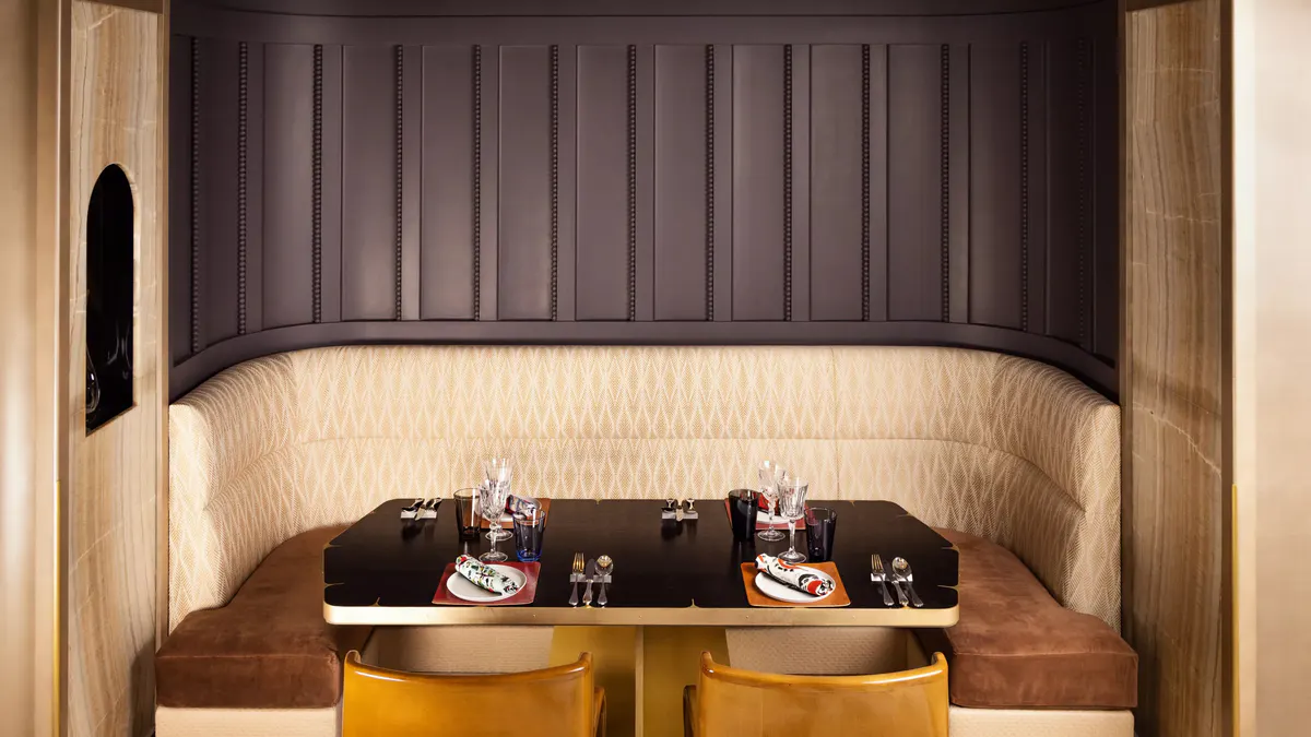 Intimate dining alcove with dark upholstered banquette and copper accents