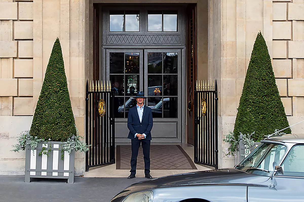 Hotel entrance with doorman, striped awning, and traditional Parisian facade