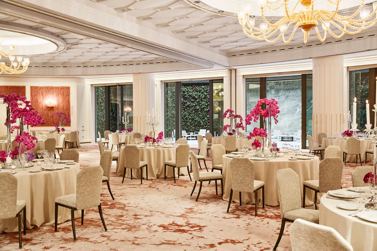 Banquet hall with cream upholstered chairs, crystal chandeliers, and floral centerpieces