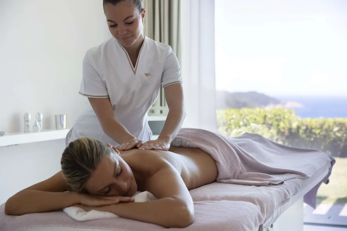 Spa therapist performing massage on guest overlooking the sea