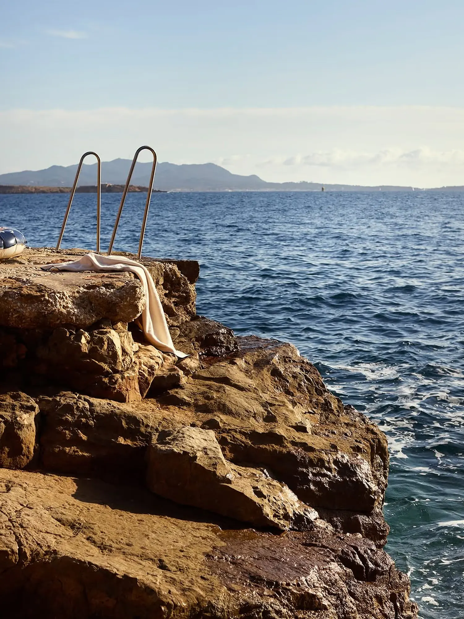 A swim ladder on a rocky Mediterranean point, open sea beyond
