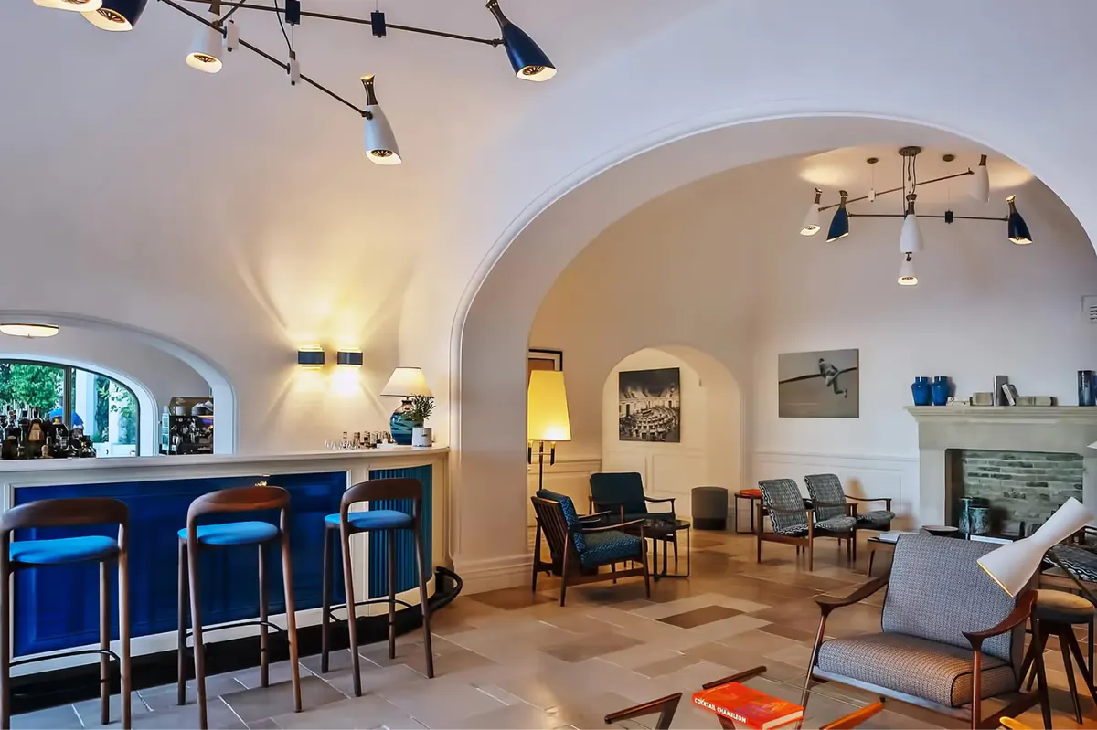 Bar area with blue velvet seating and arched stone ceilings, light fixtures overhead