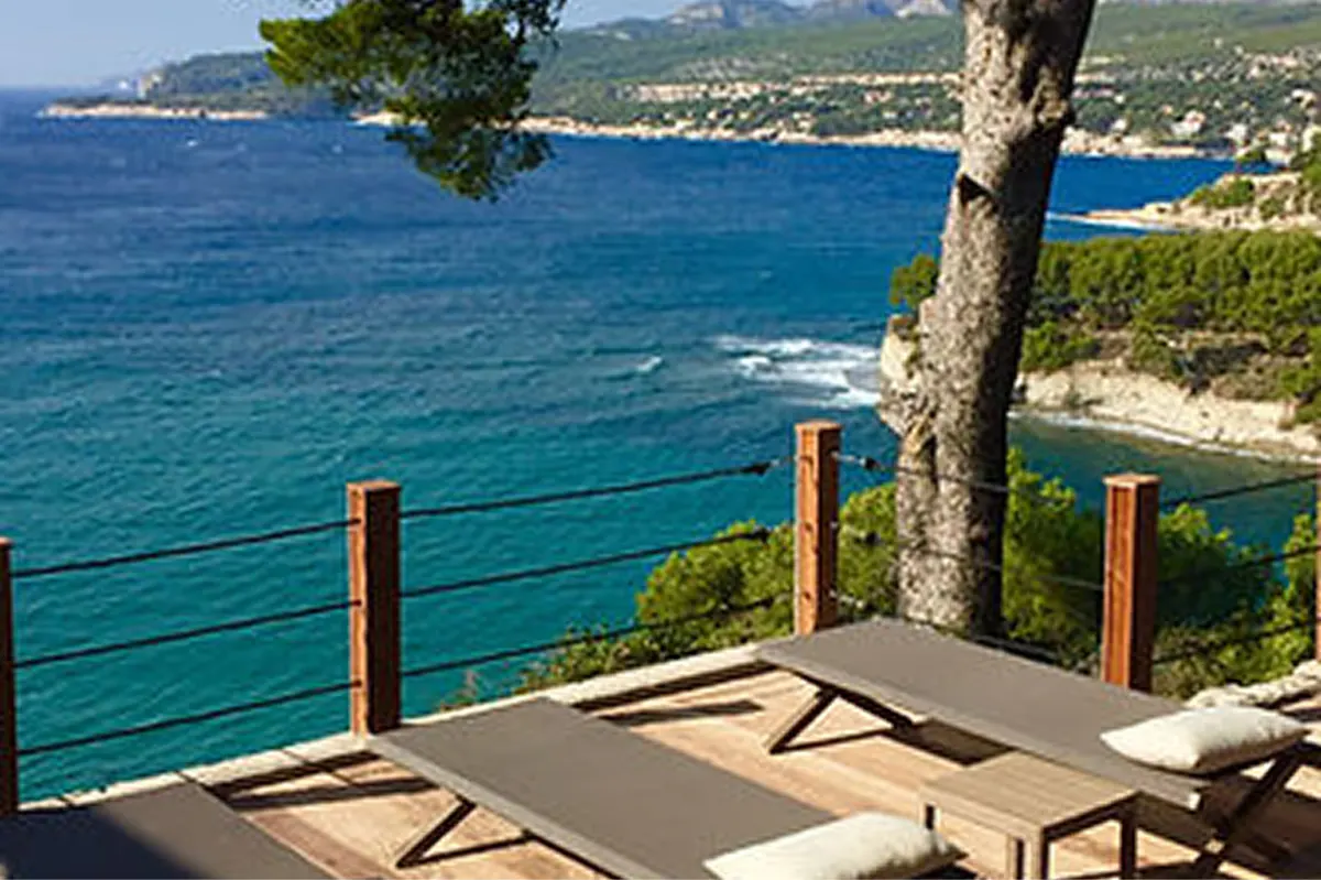 Yoga class on seaside terrace with participants in stretching poses and Mediterranean view