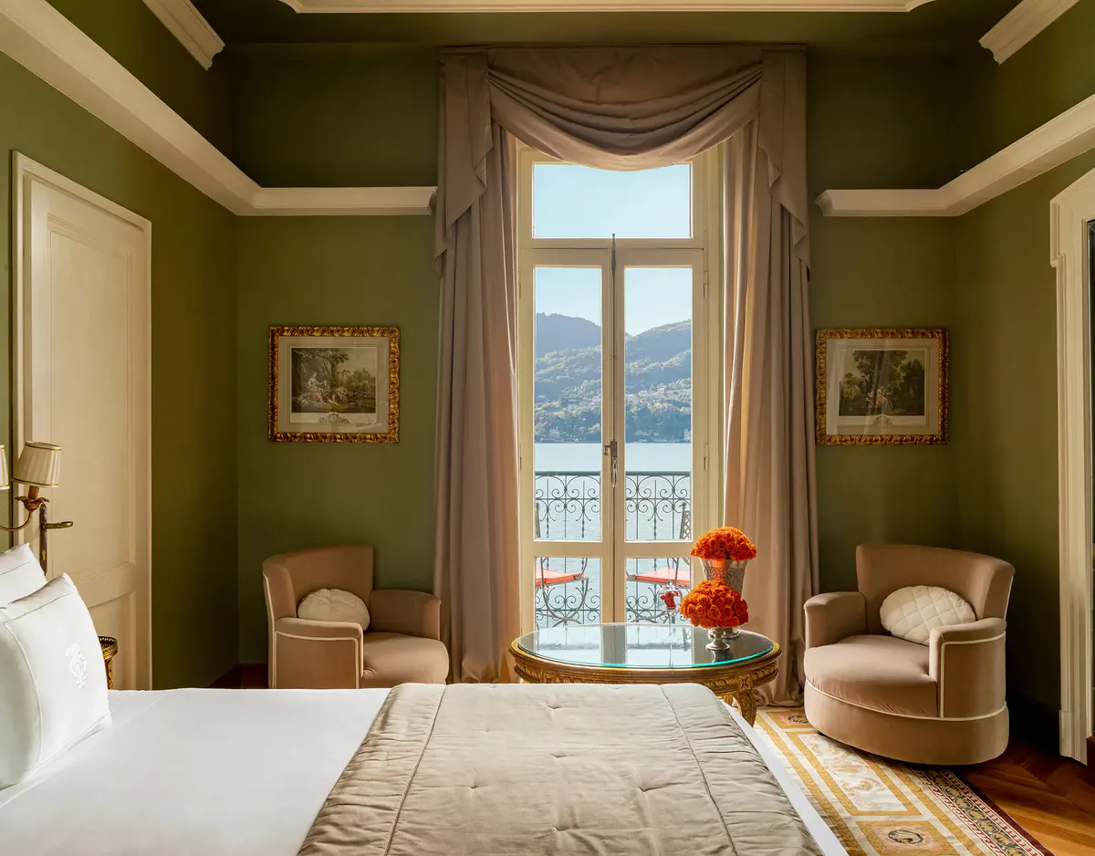 Bedroom with sage walls, armchair seating, and balcony with lake panorama