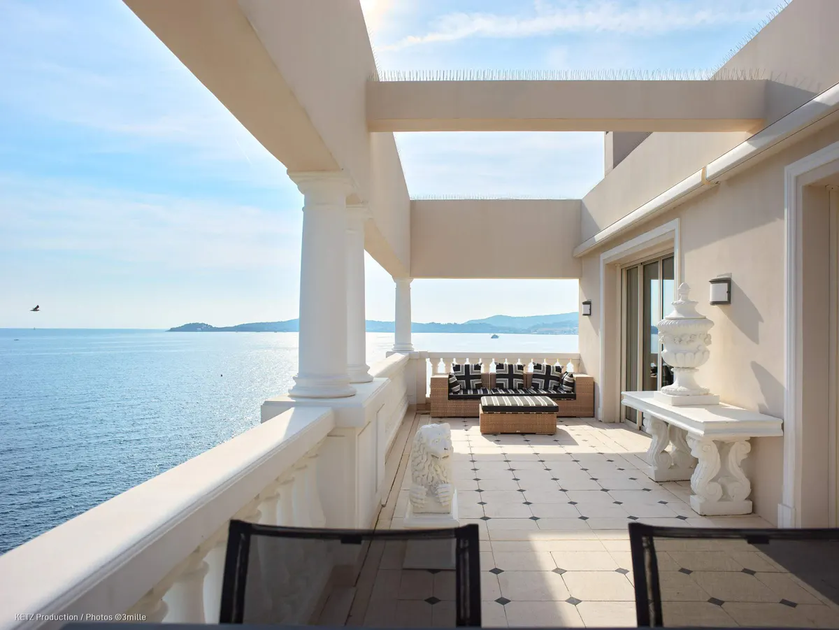 A modernist terrace with white columns overlooks calm Mediterranean waters