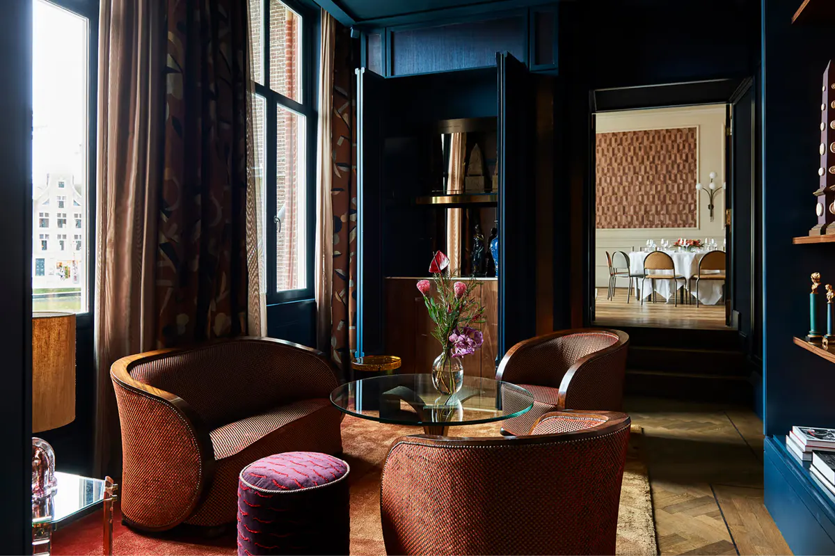 Dark blue suite sitting area with cognac leather seating and curated art display