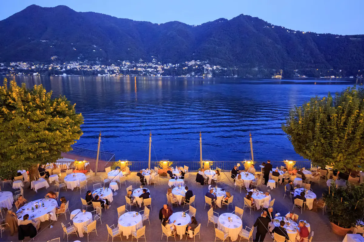 Waterfront dining pavilion at dusk with small wooden boats moored below