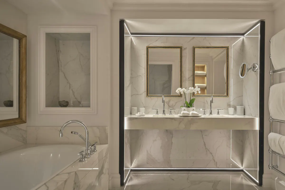 Marble bathroom with gold fixtures and a mirrored vanity cabinet