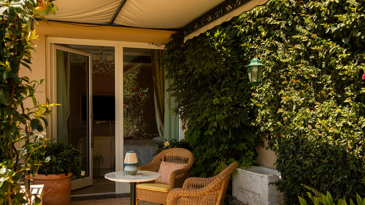 A covered outdoor terrace with lounge chair and hillside ocean view