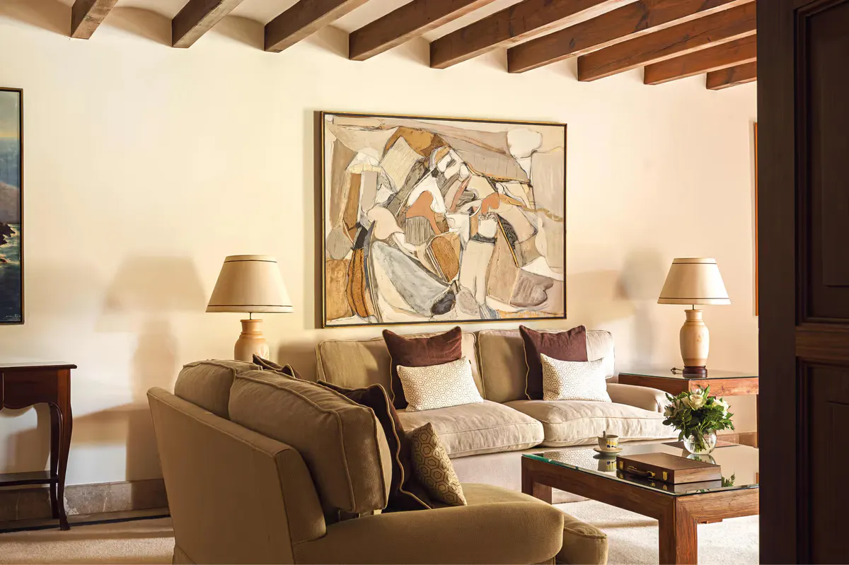 Seating area with armchairs, beamed ceiling, framed artwork, and warm natural light