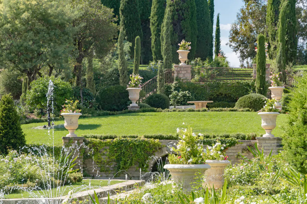 Terracotta urns and statuary on tiered garden beds with cypress groves and Mediterranean views