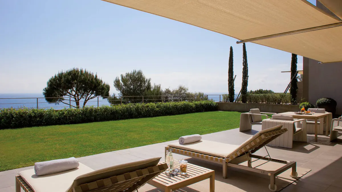 Lawn and sea views from an open terrace with wood furnishings