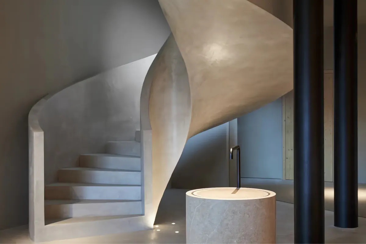 A sculptural spiral staircase with concrete and wood framing in the spa wellness area