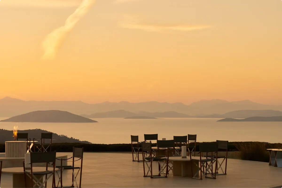 Open-air terrace dinner at golden hour with seascape vista