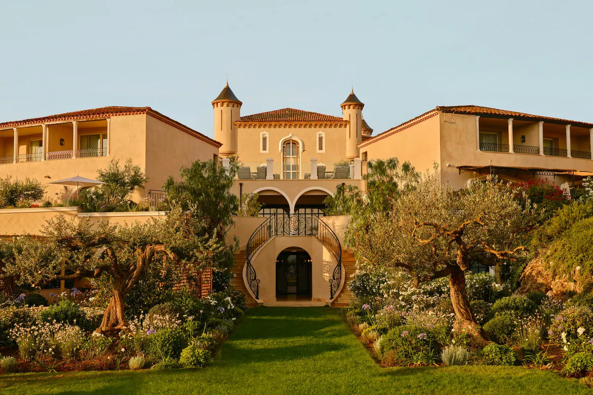 Terracotta and cream château facade with manicured gardens and cypress alleys