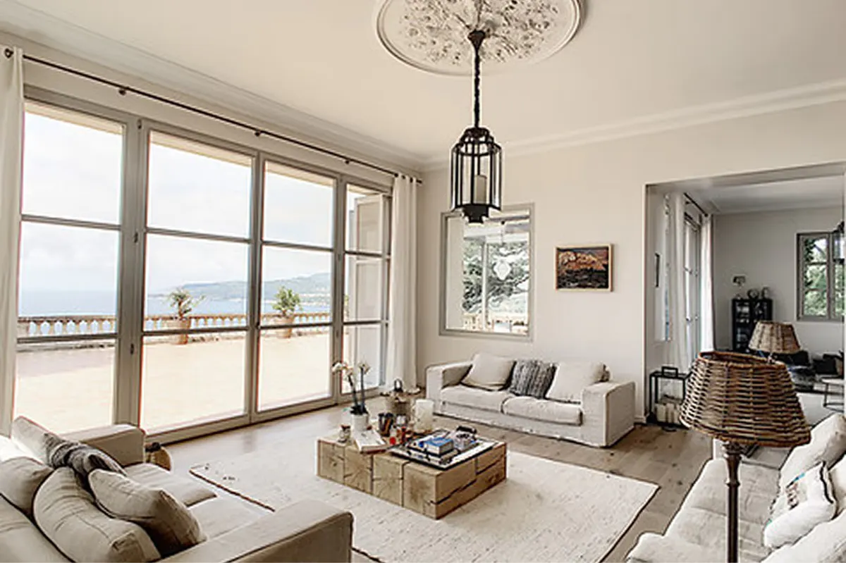 Bright living room with modern furnishings, sea views through tall windows, pendant lighting