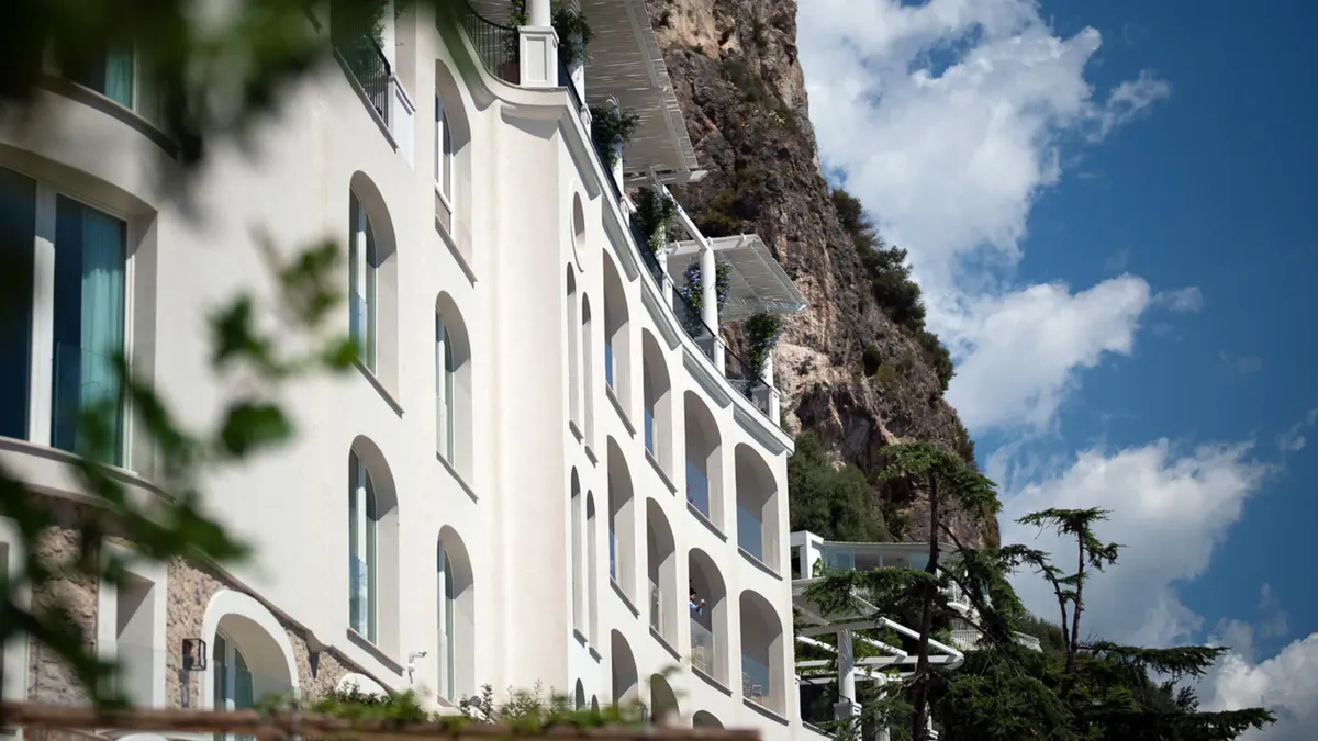 Whitewashed building facade built into rocky cliffside with Mediterranean sky