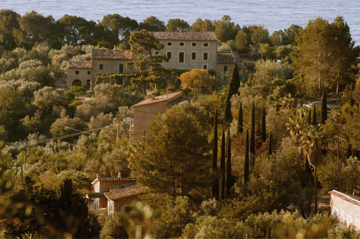 Stone manor house surrounded by cypress trees and vegetation on a Mediterranean hillside