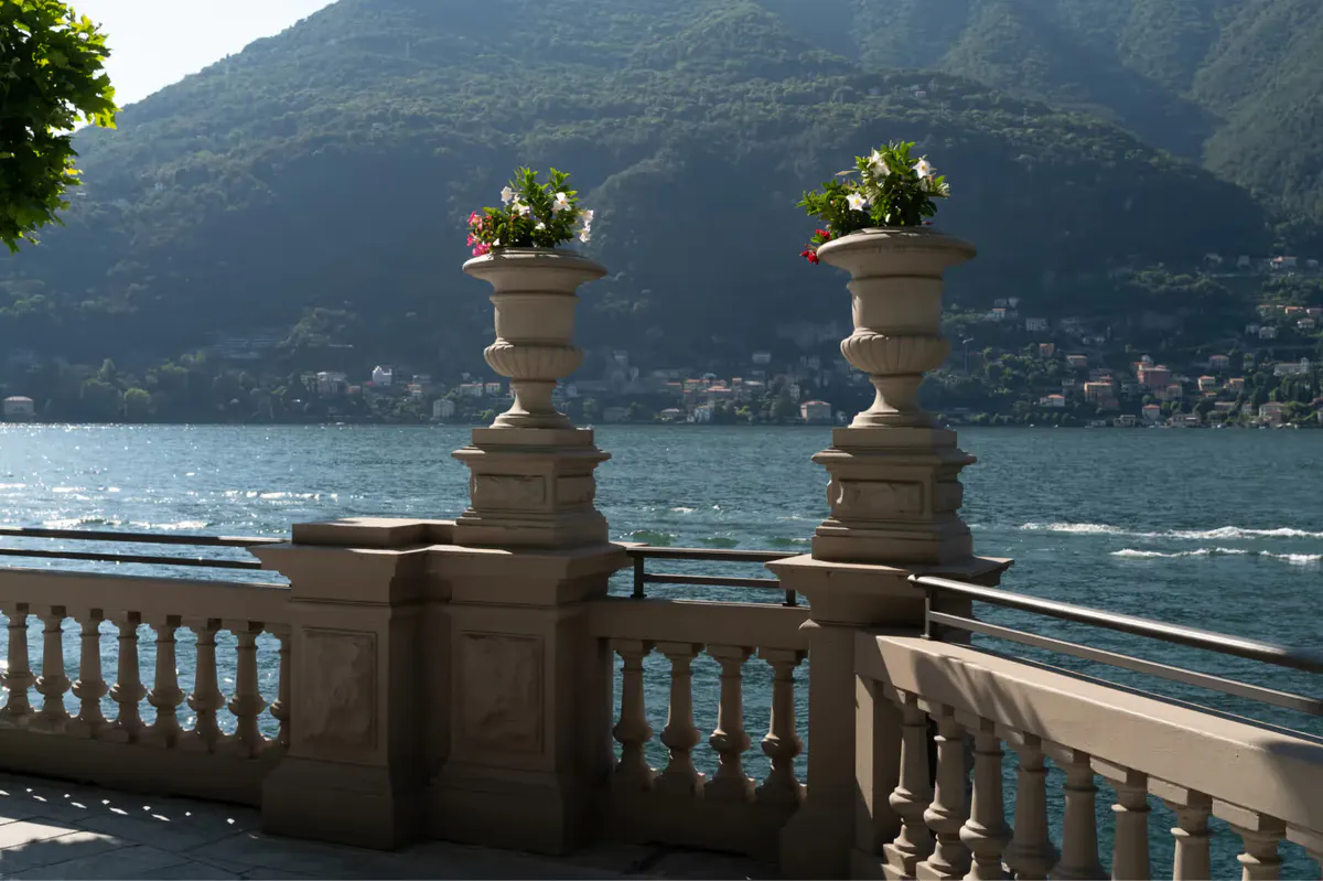 Stone balustrade with classical urns overlooking turquoise lake and surrounding mountains