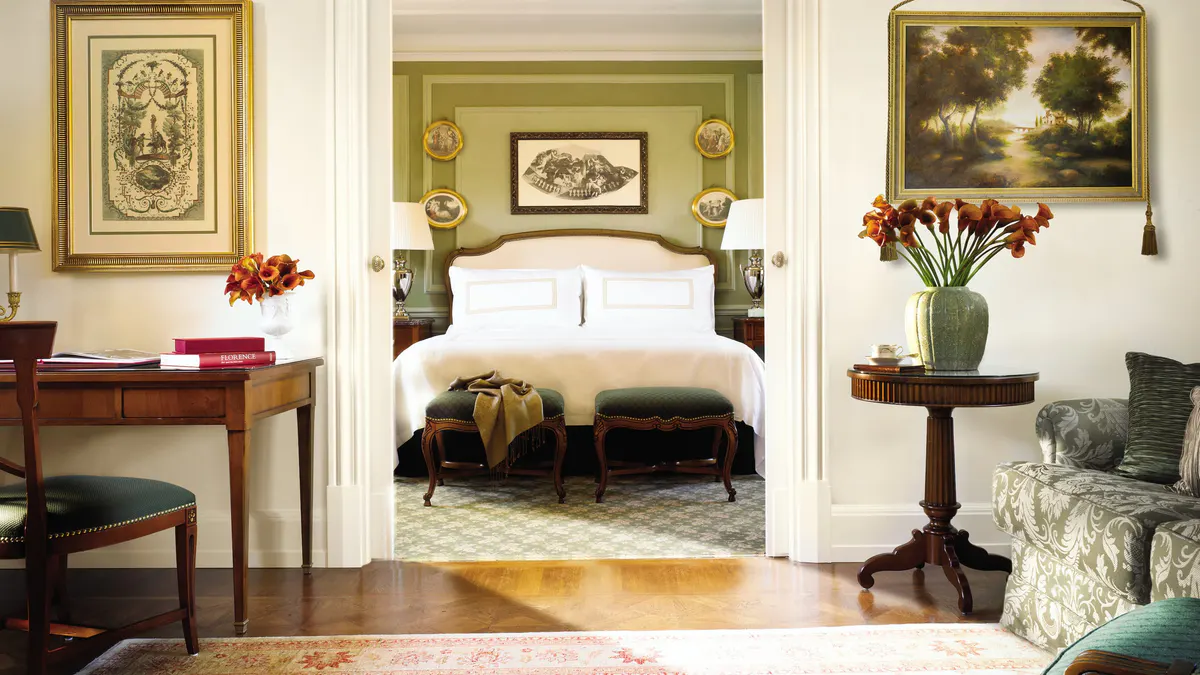 A guest suite with cream-colored walls, an ornate fireplace, and framed artworks