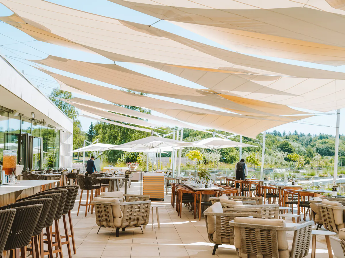 Casual outdoor terrace with striped shade canopies and furniture with vineyard views