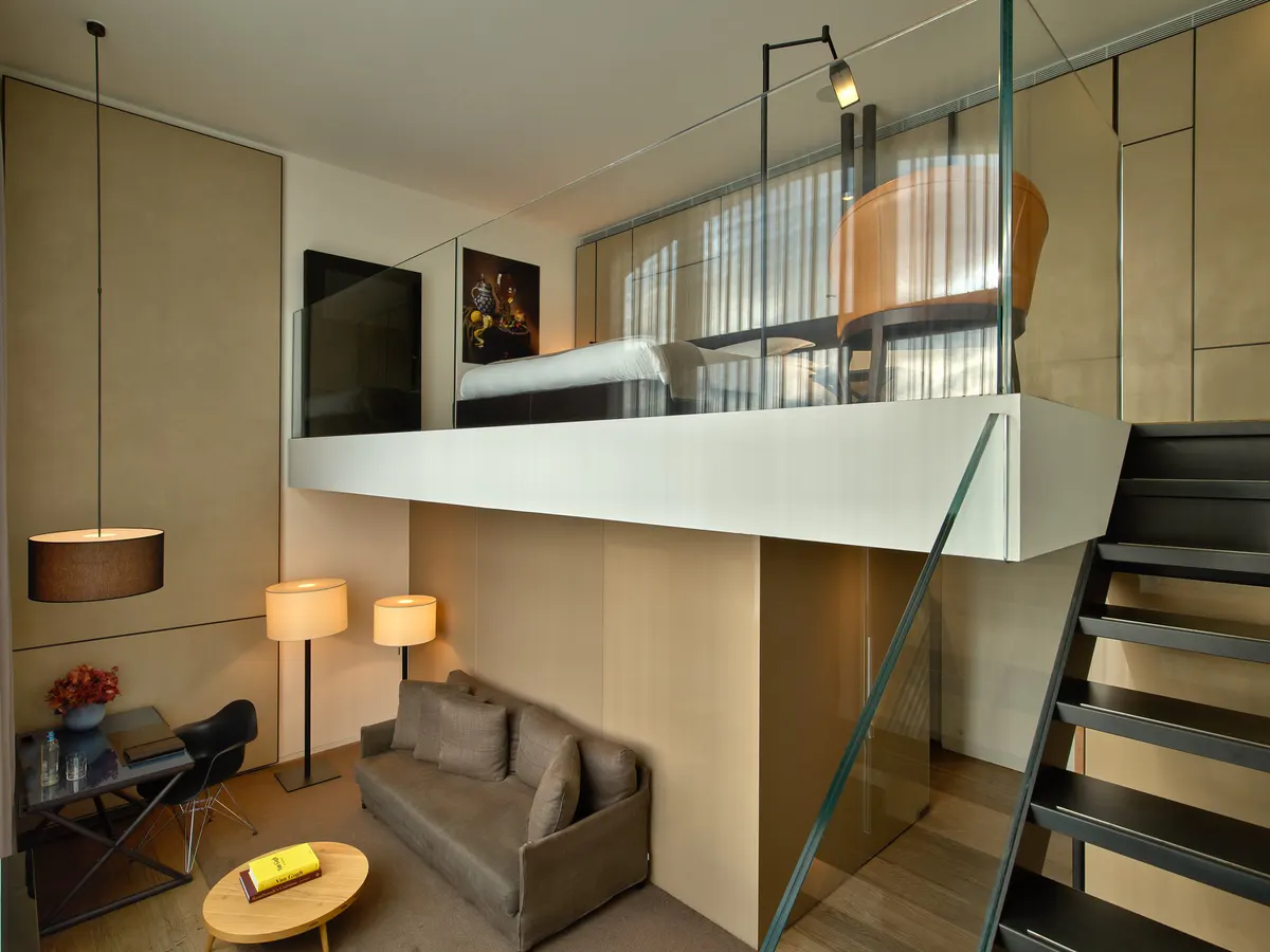 Loft-style duplex bedroom with mezzanine, natural wood finish, and staircase access