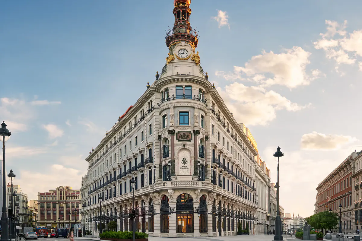 Ornate 19th-century building facade with clock tower and arched windows on a Madrid street corner