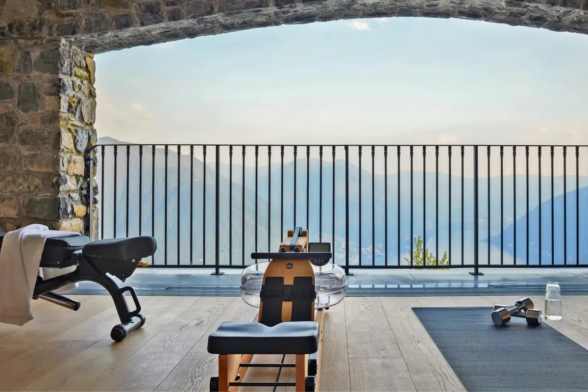 A spa room with stone walls, lounge chairs, and mountain and lake views