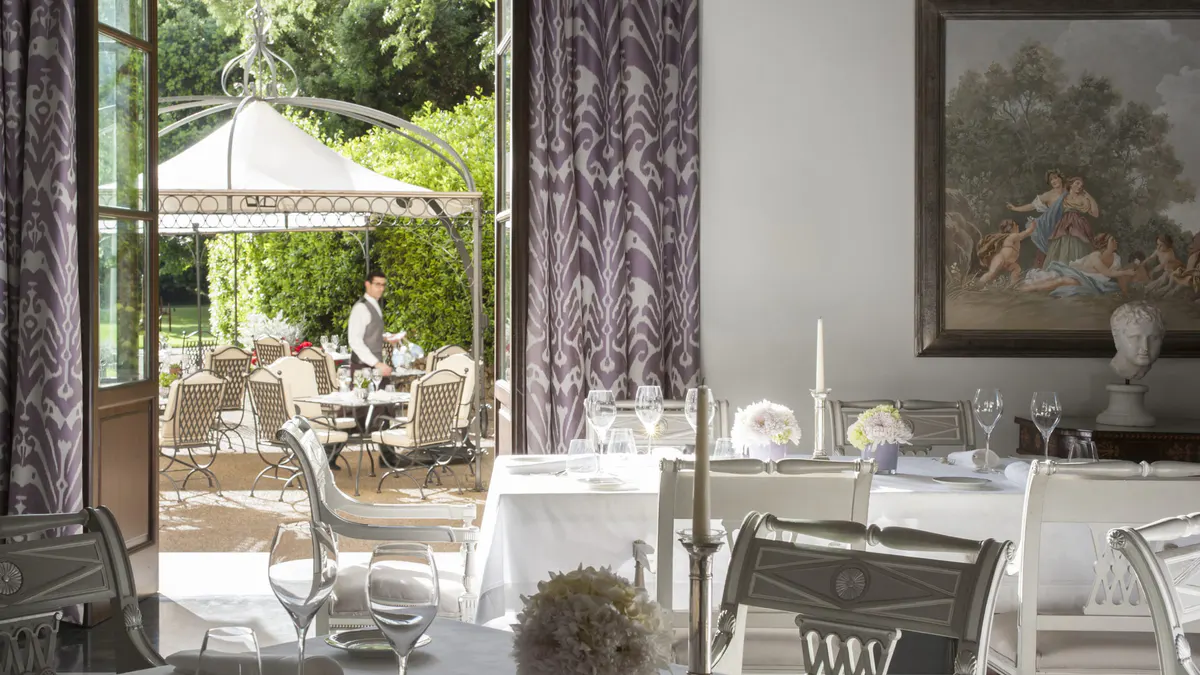 Restaurant terrace overlooking gardens with white tablecloth settings and purple drapery