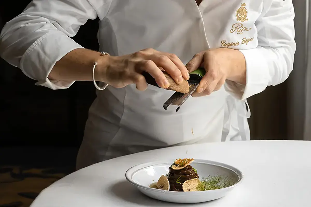 A chef’s hands preparing a plated dish with precision and artistry