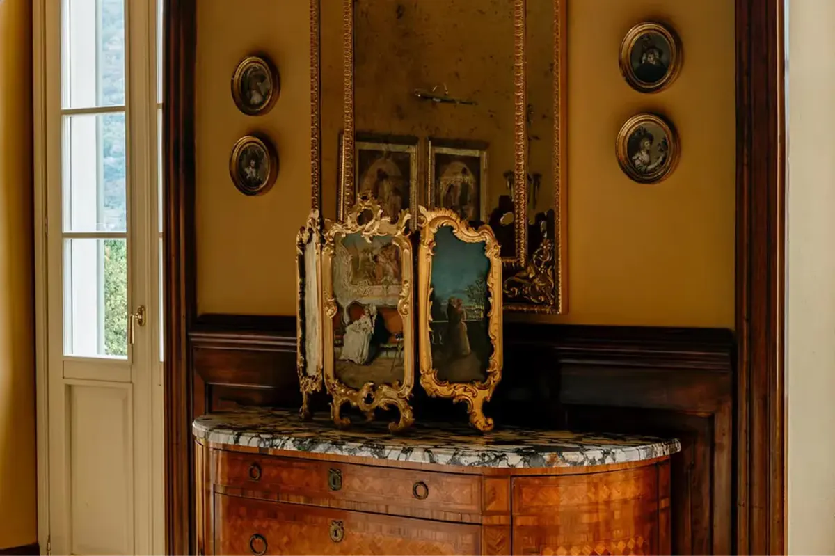A console display with ornate gold-framed mirror, portrait busts, and medallions