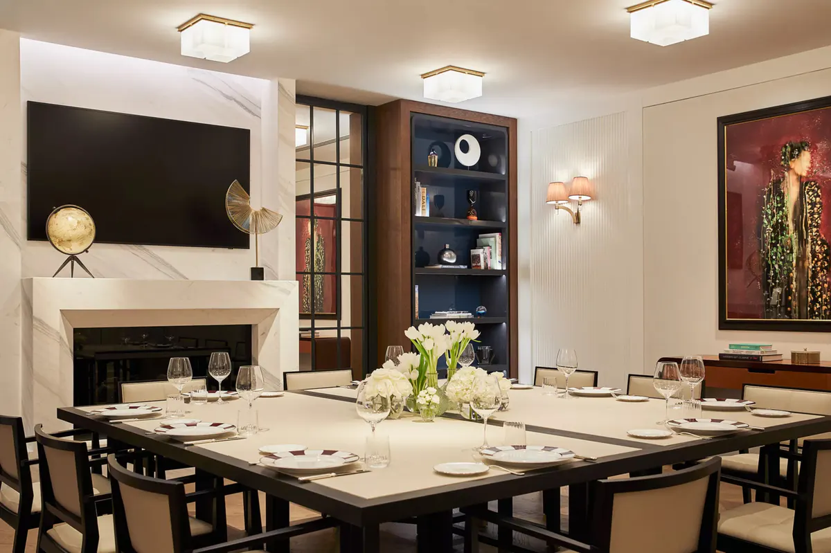 A dining room with fireplace, dark wood shelving, and black formal dining table