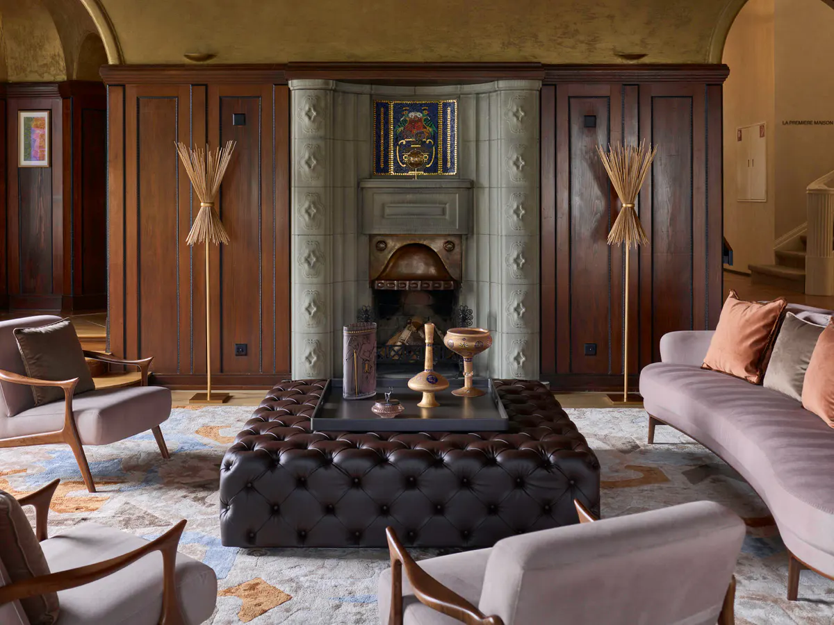 Richly furnished lounge with burgundy wood paneling, fireplace, and tufted seating