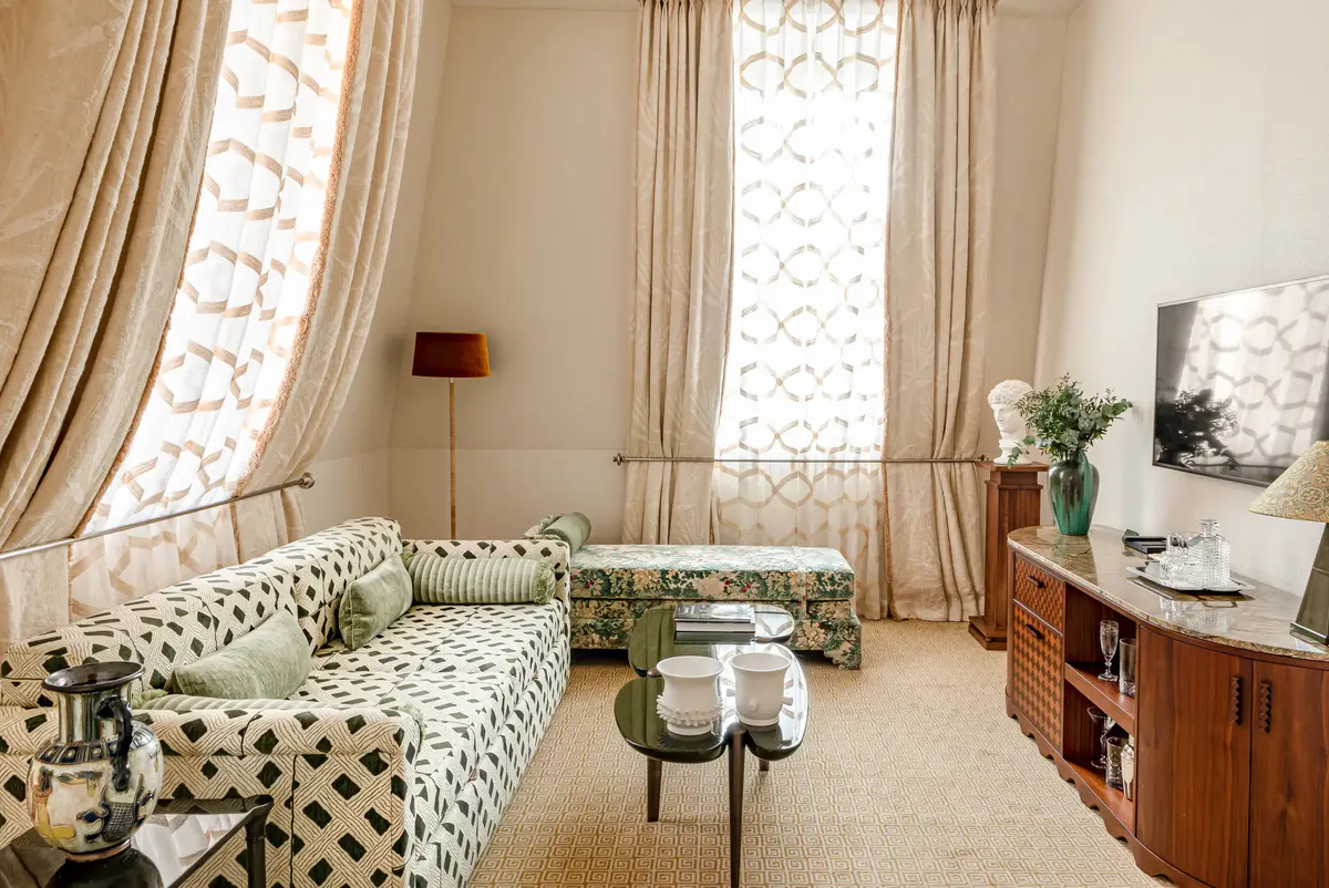 Sitting room with tall arched windows, geometric upholstered furniture, and light neutral tones
