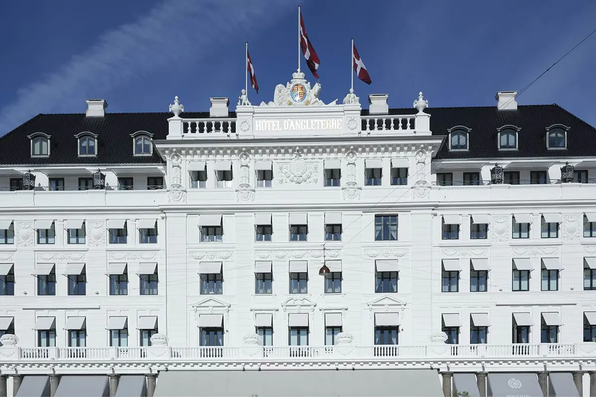 Pale facade with mansard roof and royal flags at Kongens Nytorv