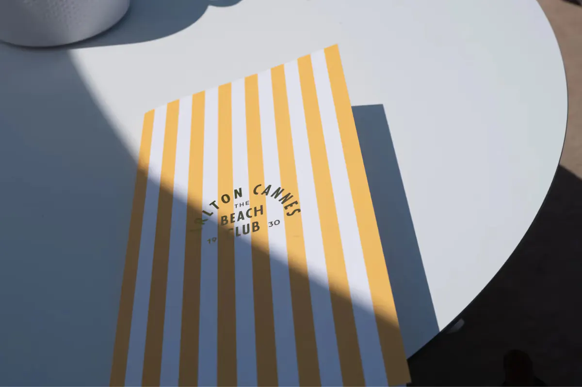 Detail of a white table with yellow striped shadow pattern from overhead structure