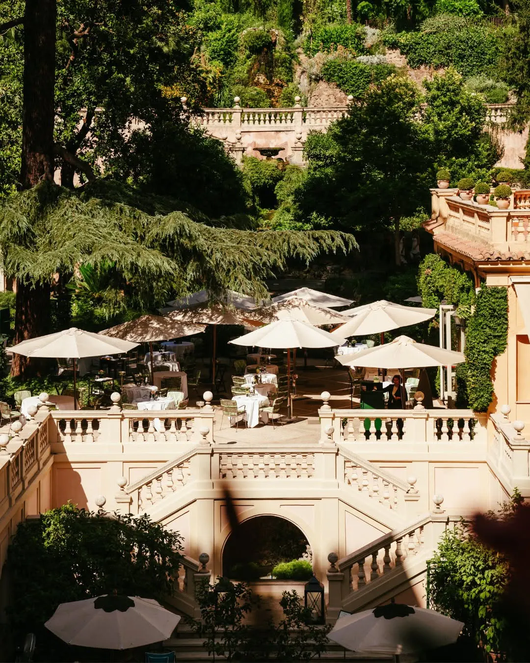 A tiered garden and balustraded stone stair below a hotel in Rome