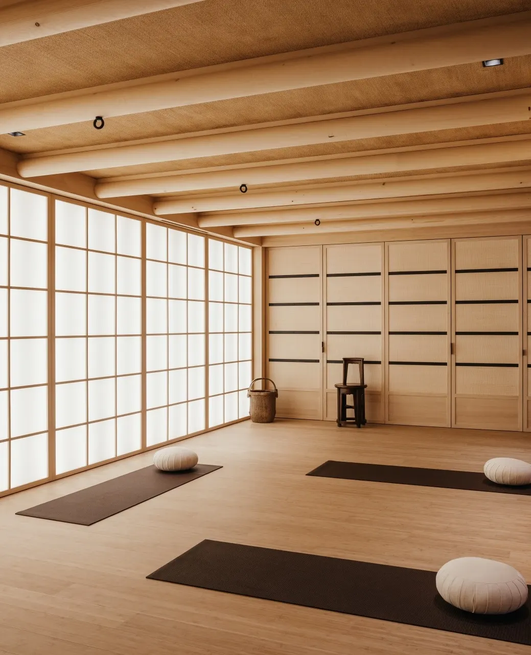 Yoga studio with shoji screen walls, timber beam ceiling, and mats set out for practice